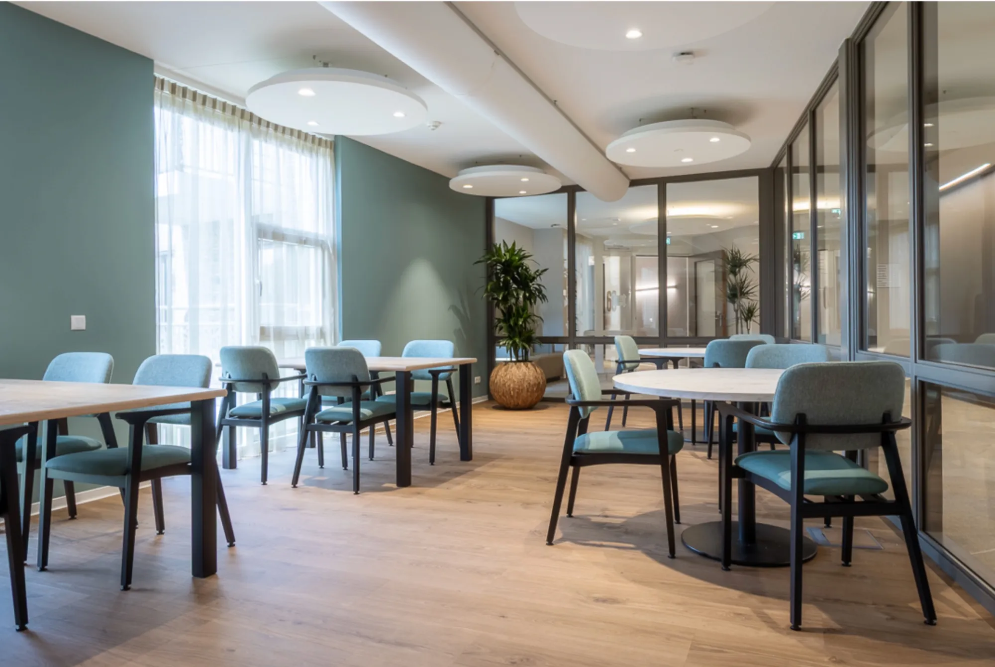 Eetruimte met blauwe stoelen en ronde tafels in De Bettekamp